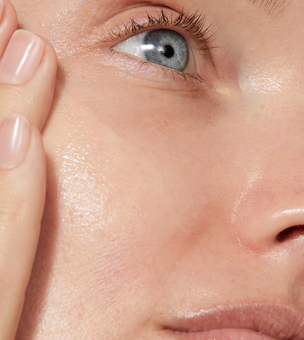 A close up of model's face with even tone applied to her skin. The skin looks glowy and smooth